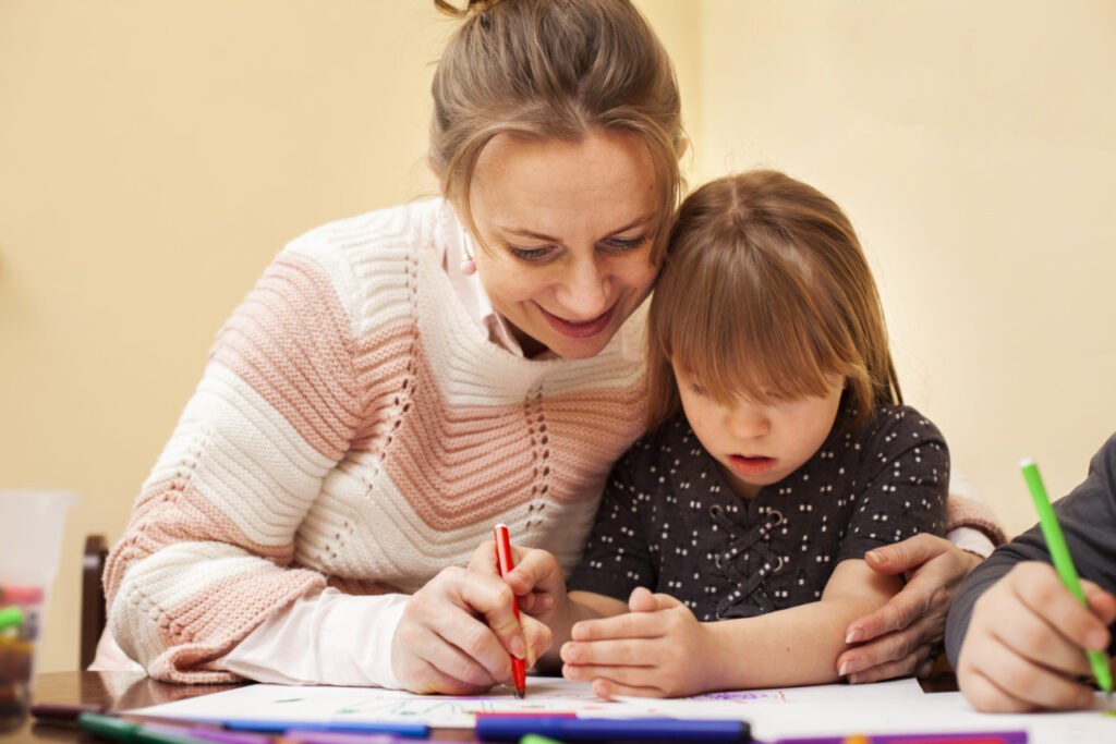 Frau und Kind mit Down Syndrom malen gemeinsam