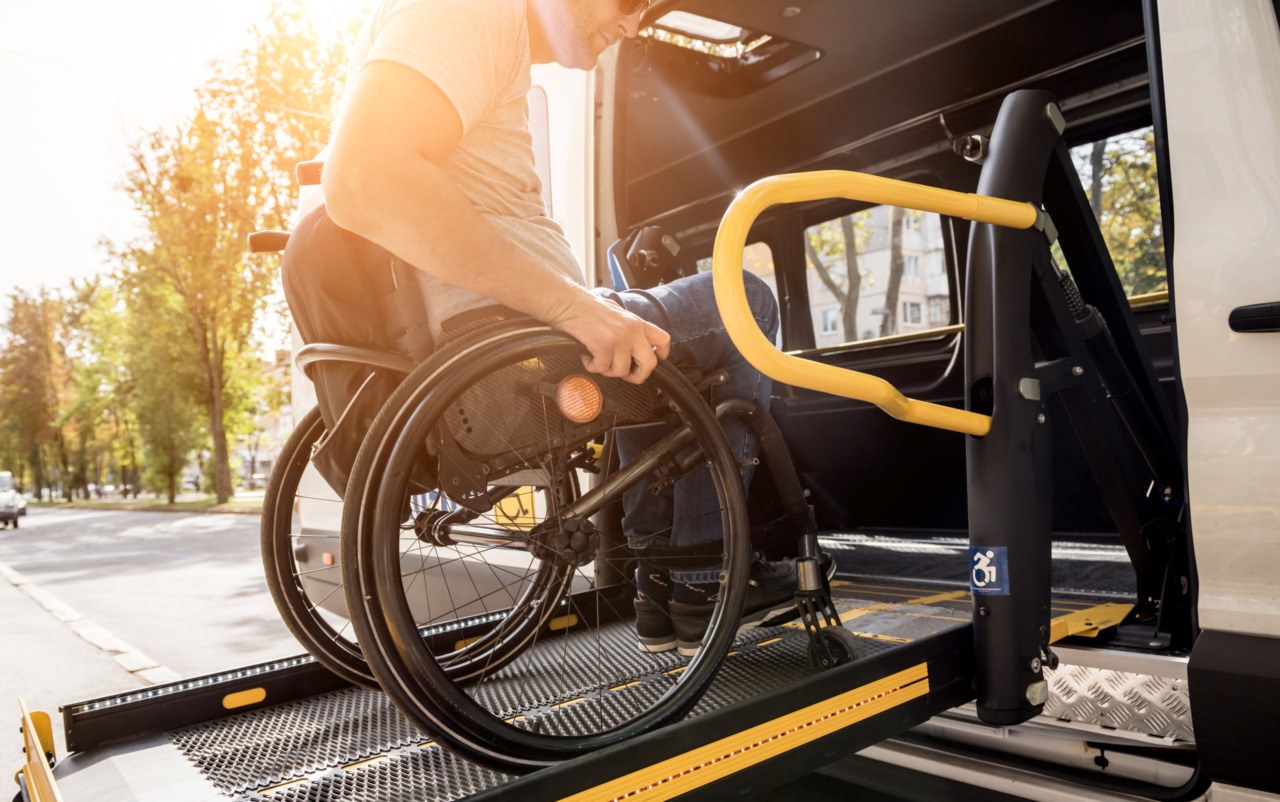 Rollstuhlfahrer benutzt Hebebühne eines behindertengerechten KFZ